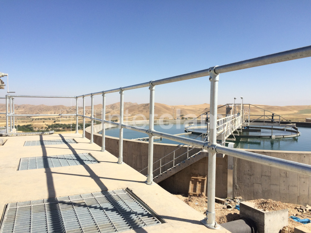 Close-up of Interclamp key clamp fittings forming robust safety balustrades and handrails at a Kurdistan water treatment facility, providing essential protection for workers.